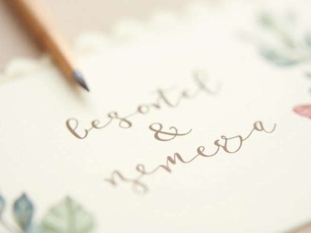 Close-up of a fine art wedding invitation with watercolor details and deckled edges.